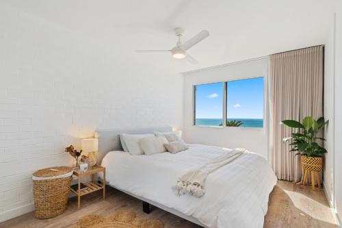 Dormitorio blanco con cama y vistas al océano en Newly renovated beach front unit. Views to die for!, en Alexandra Headland