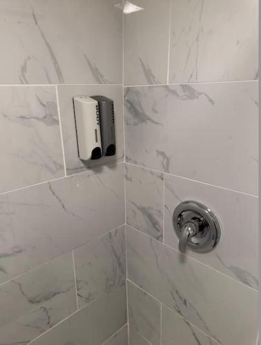a shower with a soap dispenser on a tiled wall at Guest House next to Little Italy in San Diego
