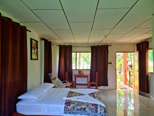 a bedroom with a bed and a table and windows at Milía Amazon Lodge in Iquitos