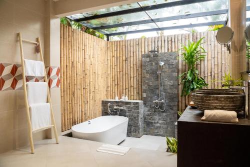 a bathroom with a tub and a toilet and a sink at Pax Ana Doc Let Resort & Spa in Ninh Hòa
