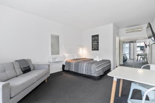 1 dormitorio con cama, sofá y mesa en Commodore Motor Inn, en Albury