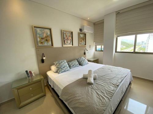 - une chambre avec un grand lit blanc et une fenêtre dans l'établissement Samaria Club de Playa Exclusivo, à Gaira