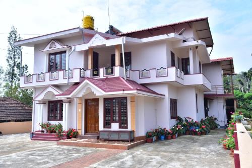 a white house with flowers in front of it at Madhuvana Homestay Coorg in Madikeri