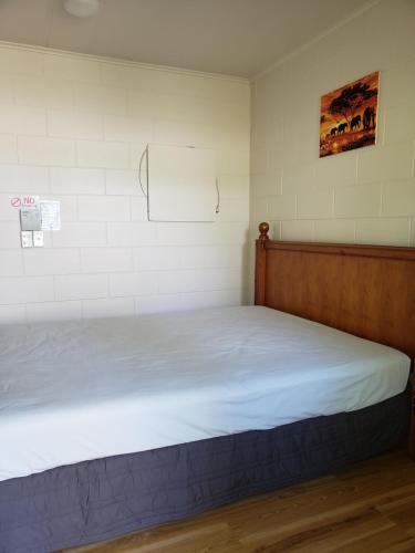 a bed in a room with white sheets and a wall at Tasman Motor Camp in Tasman