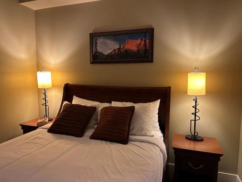 a bedroom with a bed with two lamps on it at Solara Mountain Retreat - Pool - Hot Tub - Spa - Gym in Canmore