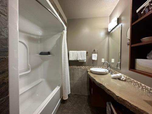 a bathroom with a tub and a sink and a bath tub at Solara Escape - 2BR Retreat with Pool - Hot Tub - Gym - Spa in Canmore