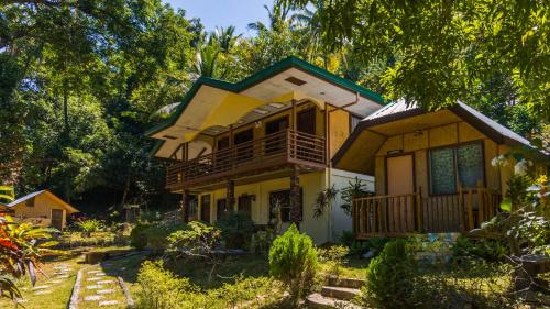 uma casa amarela com um alpendre e uma varanda em High Chaparral Cottages em El Nido