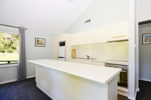 a white kitchen with a large white counter top at Beau Villa - Two bedroom Villa on golf course in Kangaroo Valley