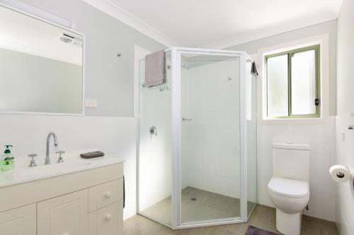 a white bathroom with a shower and a toilet at Beau Villa - Two bedroom Villa on golf course in Kangaroo Valley