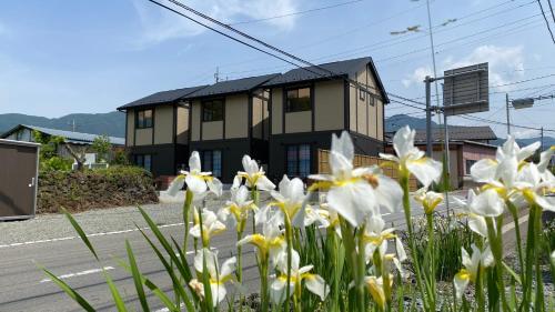 una casa con flores blancas delante de una calle en Holiday home Furinkazan 風林火山, en Fujikawaguchiko