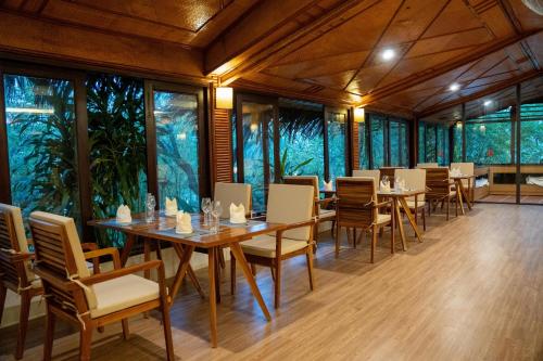 a dining room with tables and chairs and windows at Pax Ana Doc Let Resort & Spa in Ninh Hòa