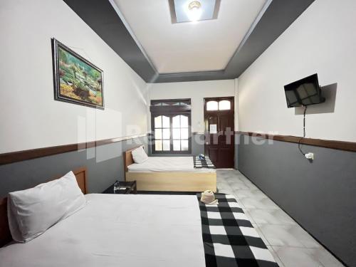 a hotel room with two beds and a tv at Hotel Dewi RedPartner near Gor Merdeka Jombang in Jombang