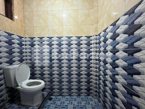 a bathroom with a toilet and blue and white tiles at Hotel Dewi RedPartner near Gor Merdeka Jombang in Jombang