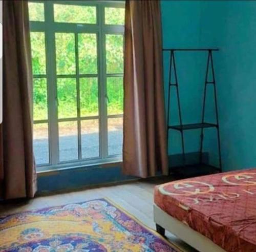 a bedroom with a bed and a window and a rug at Teratak Kayu Homestay in Batu Pahat