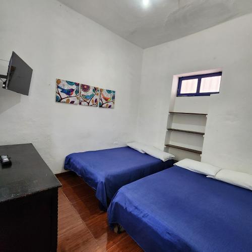 a room with two beds and a desk and a television at Posada Turistica Nakku in Silvia