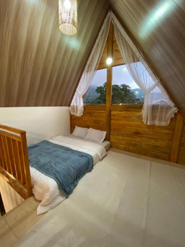 um quarto com uma cama num quarto com uma janela em Martos villa dieng em Diyeng