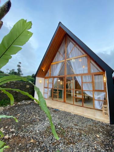 a glass house with a black roof at Martos villa dieng in Dieng