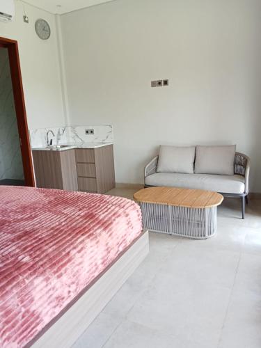 a bedroom with a bed and a couch and a table at Mesari Villa in Keramas