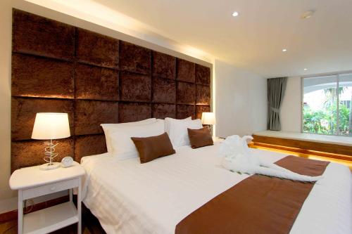 a bedroom with a large white bed with a wooden headboard at Pooh Beach Resort & Spa in Jomtien Beach