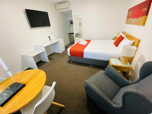 a hotel room with a bed and a table and chairs at Colonial Lodge Motor Inn in Yass