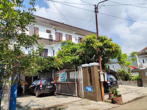 dom z samochodami zaparkowanymi przed nim w obiekcie Penginapan Nurmega jaya 