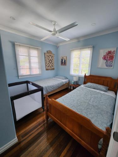 two beds in a bedroom with blue walls and wooden floors at OXLEY Mineral Pool & Private Home suburbanSTAY in Brisbane