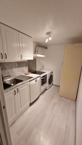 uma cozinha com armários brancos, um lavatório e uma máquina de lavar louça em Beautiful and central apartment in Oslo and Bærum em Kolsås