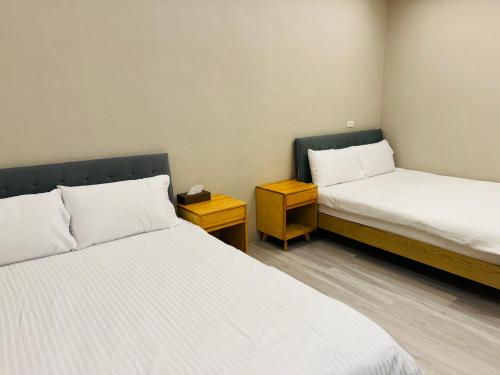 a room with two beds and a nightstand between them at Bling's House in Luodong