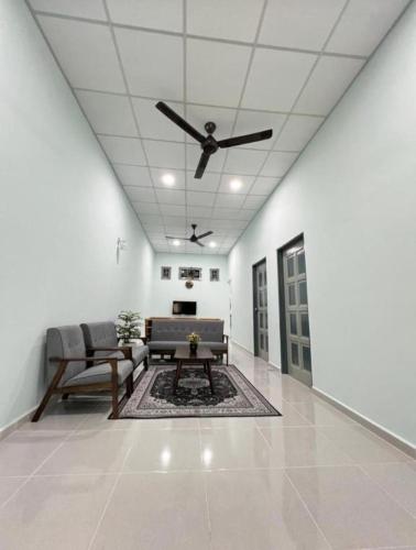 Cette chambre dispose d'un ventilateur de plafond, d'un canapé et d'une table. dans l'établissement HOMESTAY UMMI KOTA BHARU, à Kota Bharu