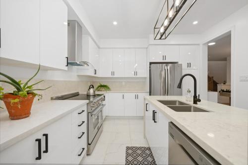 a white kitchen with a sink and a refrigerator at Luxury Whitby 4BR, Near Restaurants - Family, Pool Table, Parking! in Whitby