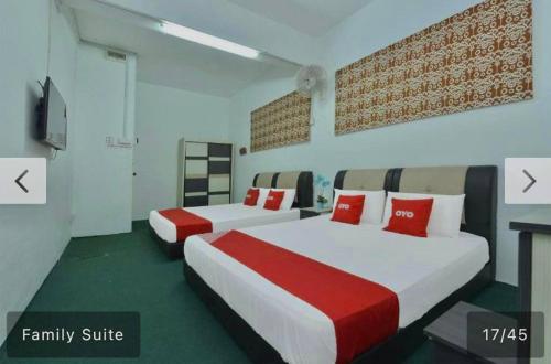 a bedroom with two beds with red pillows at SYAHIRAH HOTEL in Marang