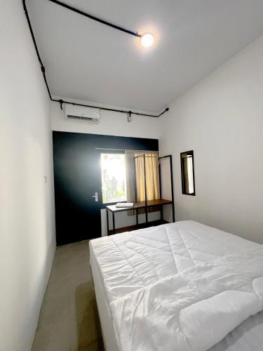 a bedroom with a white bed and a window at White House Malioboro in Jetis