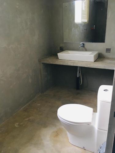 a bathroom with a white toilet and a sink at Coconut House in Panadura