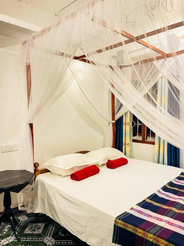 sypialnia z łóżkiem z 2 czerwonymi poduszkami w obiekcie Shanika Guest & Villa w mieście Mirissa