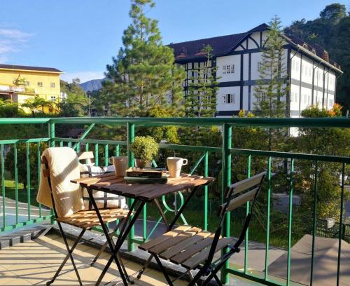 a wooden table and chairs on a balcony at Prima Villa Apartment Tanah Rata Cameron Highland in Tanah Rata