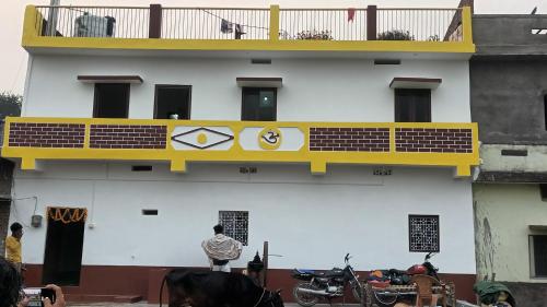 a white building with a yellow balcony and motorcycles on it at Sujata Buddha Homestay in Bodh Gaya