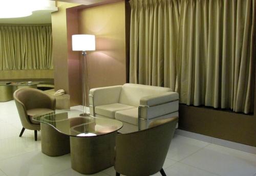 a living room with a couch and a table and chairs at Cocoon Luxury Business Hotel in Dhanbād