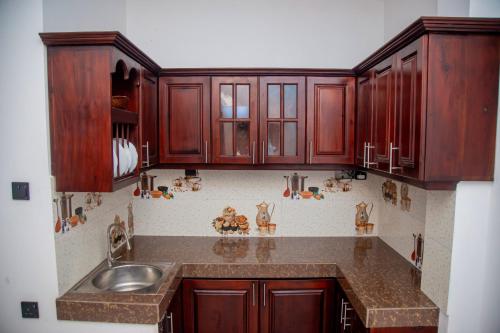 a kitchen with wooden cabinets and a sink at Eden Sea View in Talpe