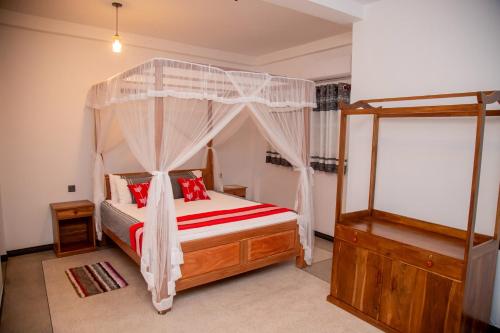 a bedroom with a canopy bed with red pillows at Eden Sea View in Talpe