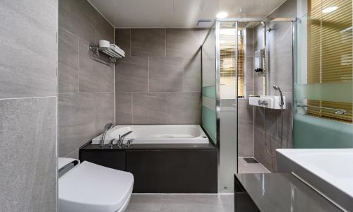 uma casa de banho com uma banheira, um WC e um lavatório. em Golden Tulip Essential Namgang em Jinju