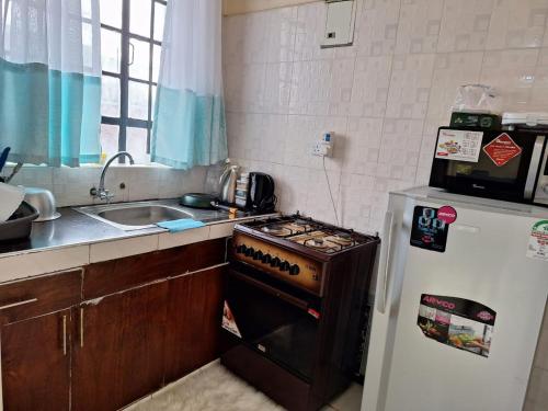 a kitchen with a stove and a sink and a refrigerator at Joyful homes Air Bnb in Naivasha