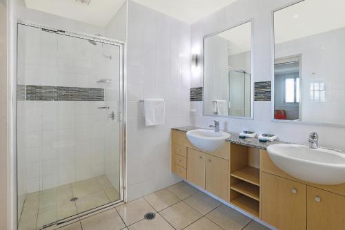 a bathroom with two sinks and a shower at Pandanus Court in Caloundra