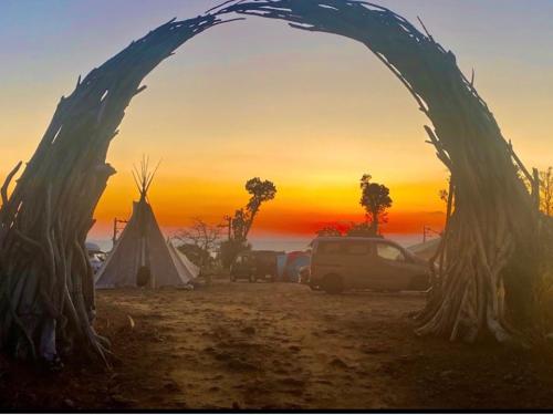 an arch with a tent and a sunset in the background at Yamamizuki in Shimanto