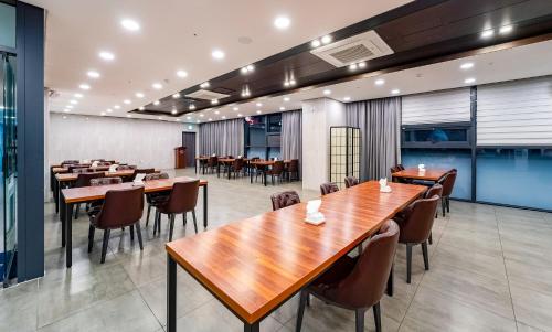 uma sala de jantar com mesas e cadeiras de madeira em Golden Tulip Essential Namgang em Jinju