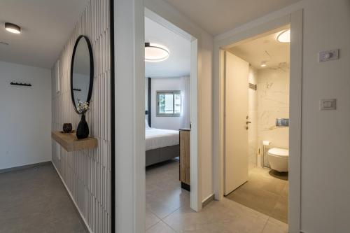 a bathroom with a mirror and a bedroom with a bed at Seaside Haven-City Center Amazing Pool and Sea view in Eilat