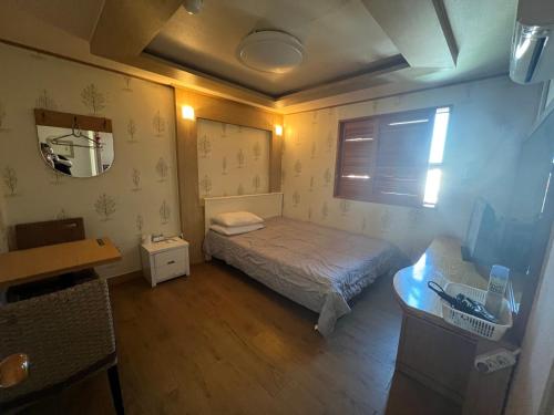 a small bedroom with a bed and a mirror at Greenpeace Motel in Gangneung