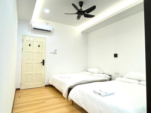 two beds in a room with a ceiling fan at Grace Homestay Tawau in Tawau