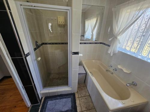 a bathroom with a shower and a tub and a sink at Secure Private Flatlet in Newton Park in Port Elizabeth