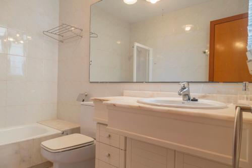 a bathroom with a sink and a toilet and a mirror at Can Francesc Wifi, BBQ, garden, 200m from the beach for 8 in Port d'Alcudia