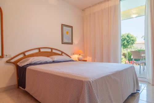 a bedroom with a bed and a large window at Can Francesc Wifi, BBQ, garden, 200m from the beach for 8 in Port d'Alcudia